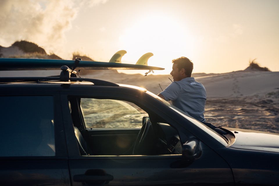 Ivo Cação at sunset with surfboards on the roof rack in Figueira da Foz, Portugal